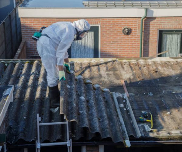 Professional asbestos removal. Men in protective suits are removing asbestos cement corrugated roofing