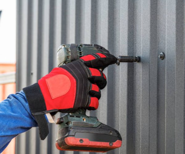 The master works as a wrench with a profiled sheet. The specialist fastens the corrugated board.