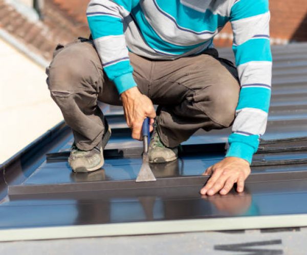 Roofer assembles sheet metal on the roof. Construction workers - installation assembly of new roof. Roofing tools.