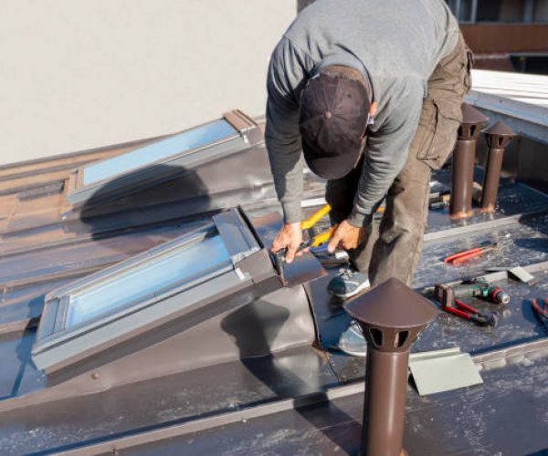 A craftsman covers the roof window with sheet metal. Roofer and window master work.