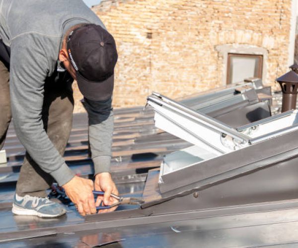 The craftsman covers the skylight with sheet metal. Roof windows mounted in a roof covered with an aluminum sheet. A roofer and window master work.