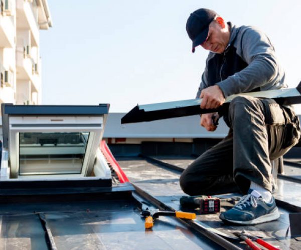 The craftsman covers the skylight with sheet metal. Roof windows mounted in a roof covered with an aluminum sheet. A roofer and window master work.