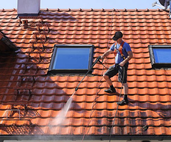 Worker is cleaning the roof and rainwater gutter with high pressure.